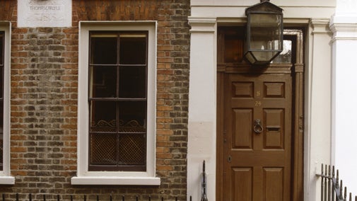 An image of the front of the red bricked Carlyle's House in London with a wooden door and a grand stepped doorway surrounded by wide, detailed stone architrave